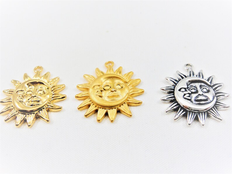 May include: Three gold-toned sun charms with a face in the center. The sun charms have a loop at the top for hanging.