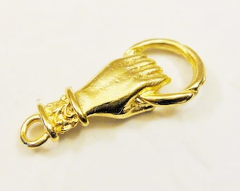 Könnte beinhalten: Goldfarbener Metall-Hand-Anhänger mit einem Ring am Finger und einer Schlaufe am Handgelenk zum Anbringen an einer Halskette oder einem Armband.