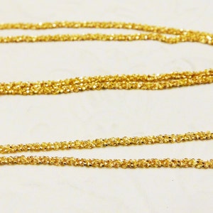 May include: A gold chain necklace with a delicate, twisted design. The chain is made of multiple strands of thin, interwoven wire.