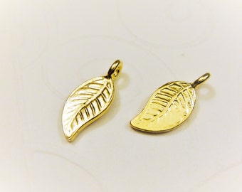 May include: Two gold leaf charms with a textured surface. The charms have a loop at the top for attaching to jewelry.