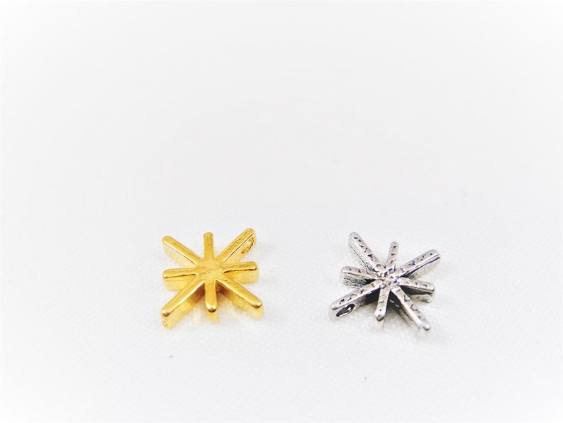 May include: Two star-shaped charms, one gold and one silver. Both charms have a detailed design with multiple points.