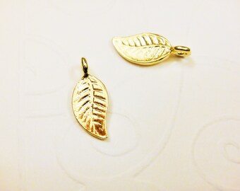 May include: Two gold leaf charms with a detailed vein pattern. The charms have a loop at the top for attaching to jewelry or other crafts.