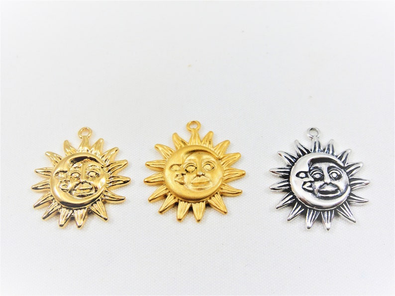May include: Three sun charms with a face on them. The charms are gold, silver, and antique silver.