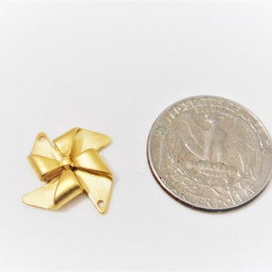 May include: Gold-colored metal bow charm with a swirl design. The charm is about the size of a US quarter.