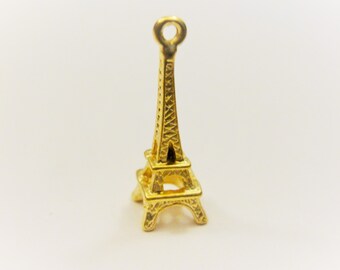 May include: A small, gold-colored Eiffel Tower charm. The miniature replica of the famous Parisian landmark features intricate architectural details and a loop at the top for attaching to a necklace or bracelet. The charm is set against a white background.