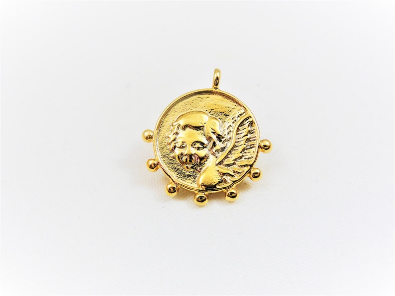 May include: Gold-toned pendant featuring a detailed angel with wings, surrounded by small beads.