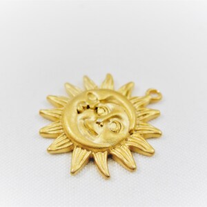 May include: Gold-toned metal sun and moon charm with a face on each. The sun has rays and the moon is a crescent shape.