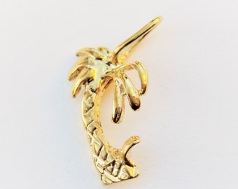 May include: A gold palm tree charm pendant. The palm tree is detailed with a textured trunk and leaves.