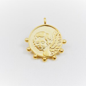 May include: Gold-toned pendant featuring a cherub with wings, surrounded by small beads.