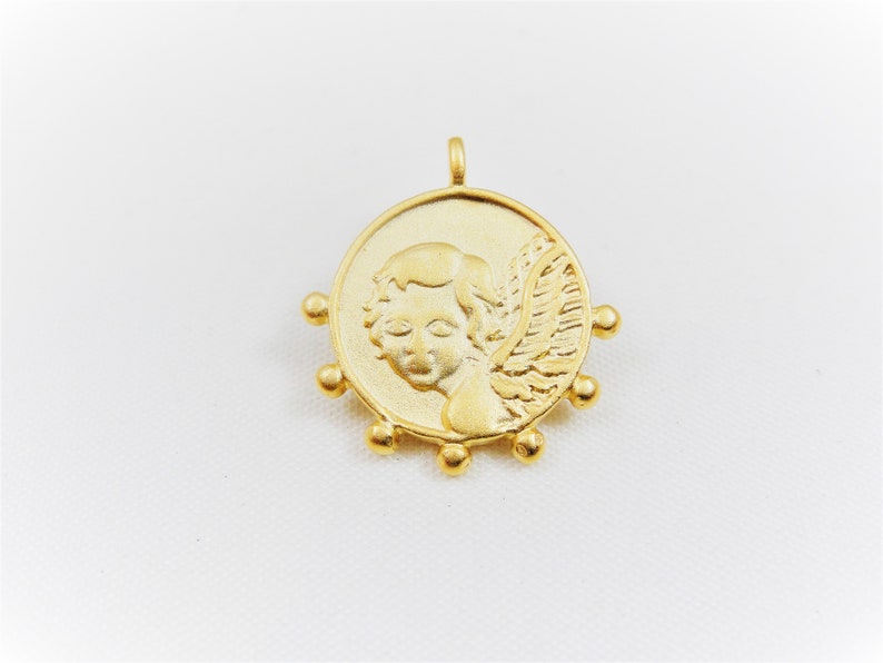 May include: Gold-toned pendant featuring a cherub with wings, surrounded by small beads.