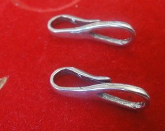 Könnte beinhalten: Zwei silberfarbene Metallverschlüsse mit einer Schlaufe an einem Ende und einem Haken am anderen. Die Verschlüsse befinden sich auf einer roten Oberfläche.