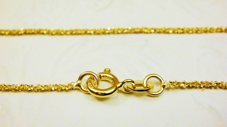 May include: A gold chain necklace with a delicate, twisted design. The chain is secured with a lobster clasp.
