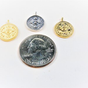 May include: Three gold and silver pendants with an eye and star design. The pendants are about the size of a US quarter.