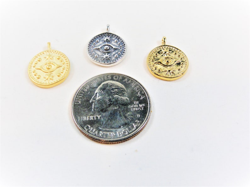 May include: Three gold and silver pendants with an eye and star design. The pendants are about the size of a US quarter.