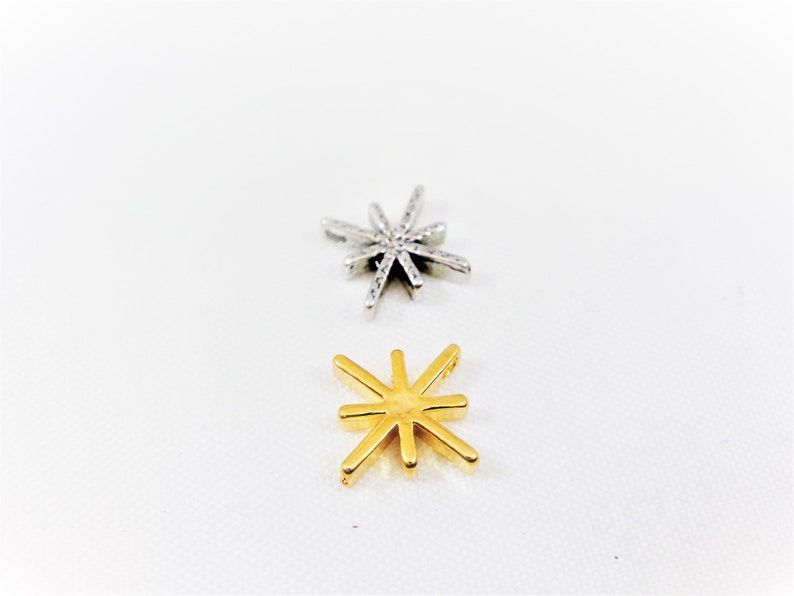 May include: Two star-shaped charms, one silver and one gold. Both charms have eight points.