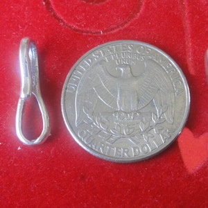 May include: Two silver metal clasps for jewelry making. The clasps are about the size of a US quarter.
