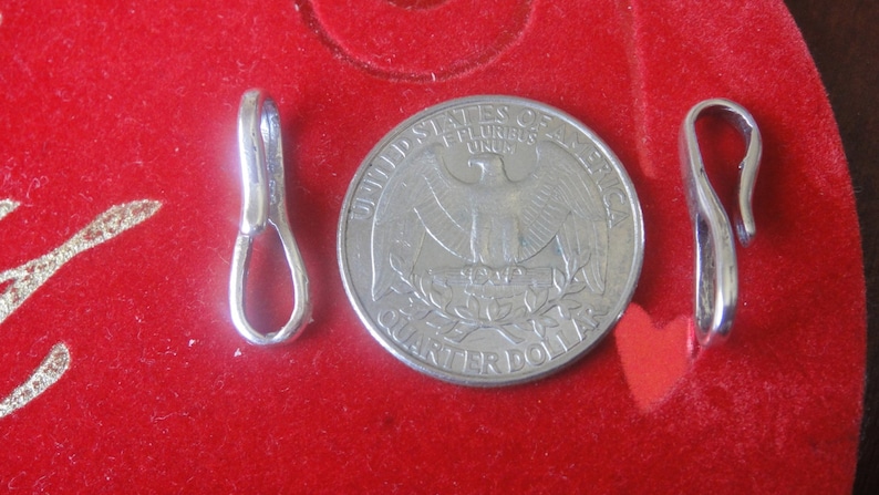 May include: Two silver metal clasps for jewelry making. The clasps are about the size of a US quarter.