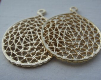 May include: Two gold-coloured metal circular pendants with a delicate, intricate, openwork design. The pendants have a loop at the top for attaching to a chain or cord.