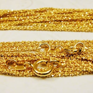 May include: A gold chain necklace with a delicate, textured design. The chain is layered and has a lobster clasp closure.