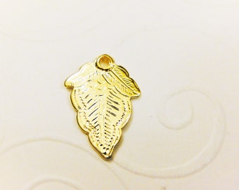 May include: A gold-colored metal leaf charm with a detailed design. The charm has a hole at the top for attaching to a necklace or bracelet.