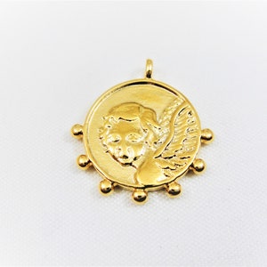 May include: Gold-toned pendant featuring a cherub with wings, surrounded by small beads.