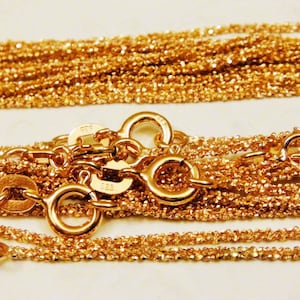 Puede incluir: Primer plano de un mont&oacute;n de cadenas de oro con m&uacute;ltiples cierres. Las cadenas son delicadas y tienen un acabado brillante.