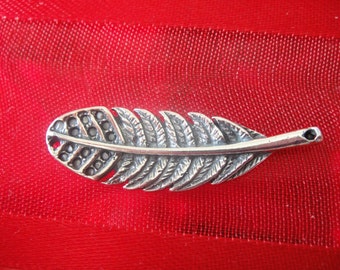 Op de afbeelding: Een zilveren veerbedel met een gedetailleerd ontwerp. De veer heeft een gat aan de bovenkant om aan een armband of ketting te bevestigen.