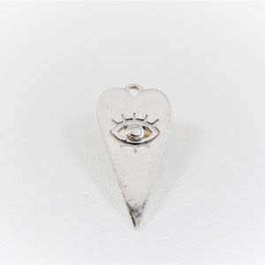 May include: Silver charm in the shape of a heart with an eye design inside.