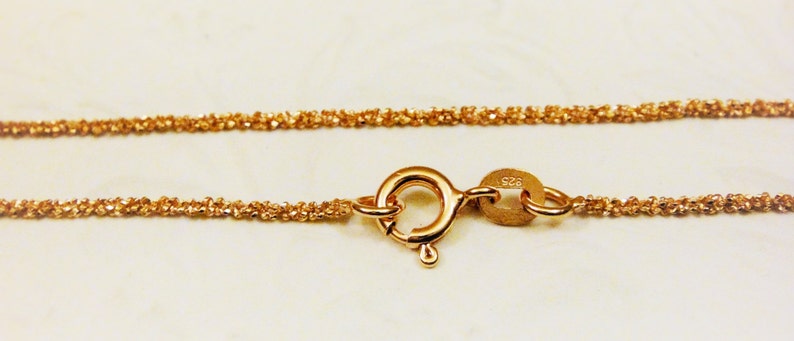 Puede incluir: Un collar de cadena de oro con cierre de mosquet&oacute;n. La cadena est&aacute; hecha de peque&ntilde;os eslabones redondos que est&aacute;n estrechamente entrelazados. La cadena est&aacute; estampada con 925.