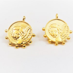 May include: Two gold-toned metal charms featuring a cherub with wings. Each charm has a circular design with a beaded border.