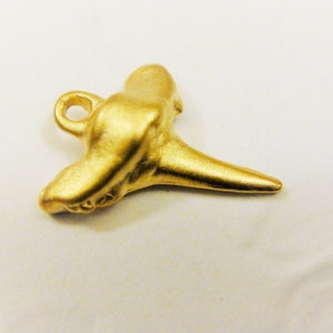 May include: A gold-colored shark tooth pendant charm with a loop for attaching to a necklace or bracelet.