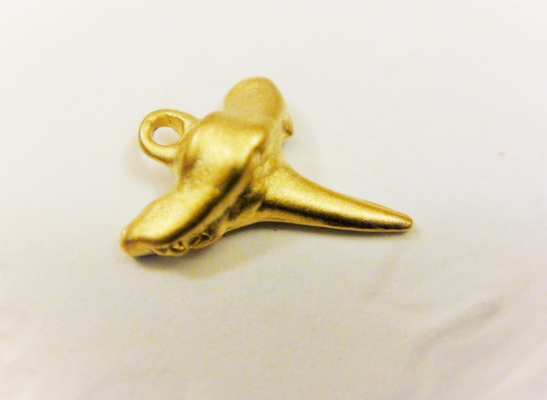 May include: A gold-colored shark tooth pendant charm with a loop for attaching to a necklace or bracelet.