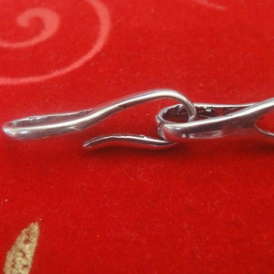 May include: Silver clasp with a curved design, suitable for attaching to a necklace or bracelet.