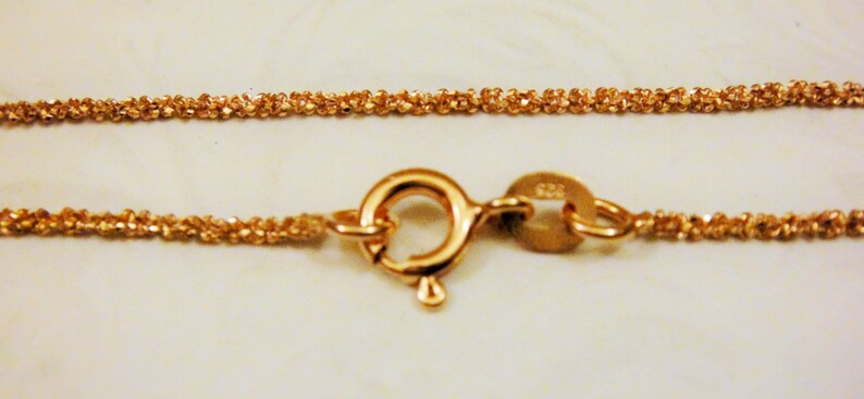 Puede incluir: Un collar de cadena de oro con cierre de mosquet&oacute;n. La cadena est&aacute; hecha de eslabones peque&ntilde;os y estrechamente tejidos.
