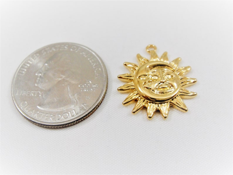 May include: Gold-toned sun charm pendant with a face and rays. The charm is about the size of a US quarter.