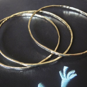 May include: Three gold-toned bangle bracelets with a hammered texture.