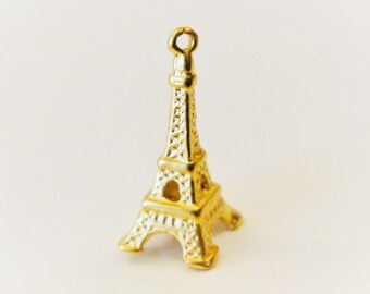 May include: A gold-colored Eiffel Tower charm with a detailed design. The charm is made of metal and has a loop at the top for attaching to a necklace or bracelet.