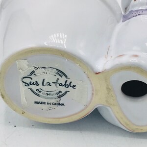 May include: White ceramic planter with a label that reads "Sur La Table" and "Made in China".