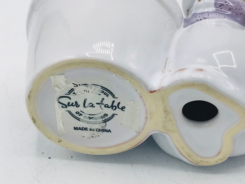 May include: White ceramic planter with a label that reads "Sur La Table" and "Made in China".