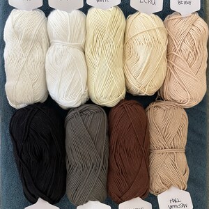 Puede incluir: Diez ovillos de lana en varios colores, incluyendo blanco, beige, marr&oacute;n, gris y negro. Los ovillos de lana est&aacute;n etiquetados con sus nombres de color.