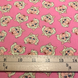 May include: Pink fabric with a repeating pattern of Miss Piggy's face. The fabric is measured with a ruler showing 14 inches.