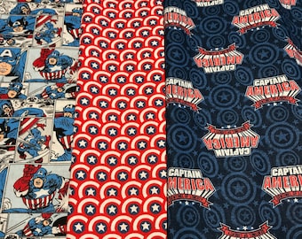 May include: Three fabric swatches featuring Captain America designs. The first swatch has a comic book style pattern with Captain America in various poses. The second swatch has a red and white pattern of stars and Captain America's shield. The third swatch has a blue background with a repeating pattern of Captain America's shield and the words "Captain America, Sentinel of Liberty".