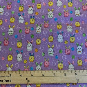 May include: Purple fabric with a repeating pattern of white bunnies, yellow chicks, and colorful polka dots. The fabric has a glittery finish.