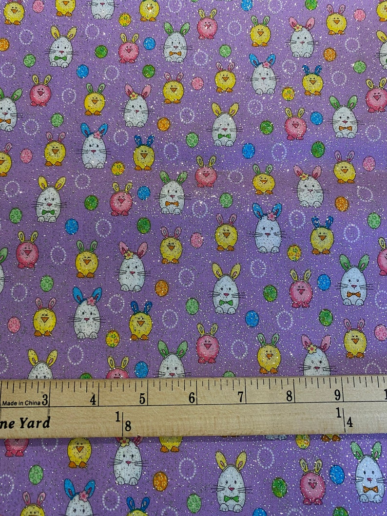 May include: Purple fabric with a repeating pattern of white bunnies, yellow chicks, and colorful polka dots. The fabric has a glittery finish.