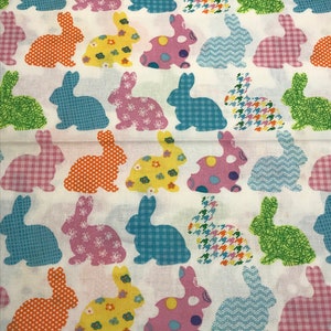 May include: A white fabric with a repeating pattern of colorful bunnies. The bunnies are in various poses and have different patterns, including polka dots, plaid, and floral designs.