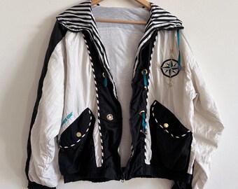 Könnte beinhalten: Vintage Windjacke in Creme, Schwarz und Weiß. Die Jacke hat ein Kompassrosen-Design, schwarze Taschen und einen gestreiften Kragen. Der Text "WHITE STAR" ist auf der linken Seite der Jacke zu sehen.
