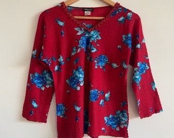 Könnte beinhalten: Rotes Langarmhemd mit blauem Blumenmuster und einem gewellten Ausschnitt. Das Hemd hat ein "Lizwear"-Etikett.