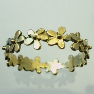 Peut inclure: Une bague en or avec un d&eacute;licat motif de petites fleurs autour de la bande.
