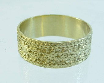 May include: A gold band ring with a textured design featuring a repeating pattern of small flowers.