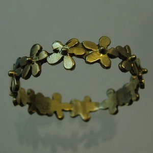 Peut inclure: Une bague en or avec un motif de petites fleurs autour de la bande.